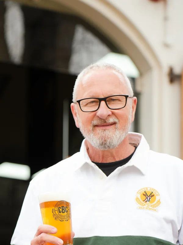 Wolfgang Koedel, founding brewmaster, with a glass of CBC beer at the brewery door